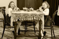 Dziewczyna bliźniacy pije herbaty przy antyka stołem z koronkowym tablecl Obraz Stock Dziewczyna bliźniacy pije herbaty przy antyka stołem z koronkowym tablecl Obraz Stock