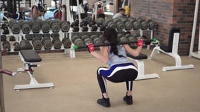 Dziewczyna kuca w gym z barbell zbiory wideo Dziewczyna kuca w gym z barbell zbiory wideo