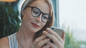 Dziewczyna pisze chłopak na smartphone i ono uśmiecha się Kobieta używa gona na telefonie komórkowym w kawiarni zdjęcie wideo Dziewczyna pisze chłopak na smartphone i ono uśmiecha się Kobieta używa gona na telefonie komórkowym w kawiarni zdjęcie wideo
