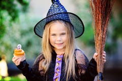Dziewczyna w czarownica kostiumu je babeczkę na Halloween zdjęcie royalty free Dziewczyna w czarownica kostiumu je babeczkę na Halloween zdjęcie royalty free
