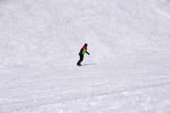 Dziewczyna w kolorowym kostiumu jest na snowboard przejażdżkach z górami zdjęcie royalty free Dziewczyna w kolorowym kostiumu jest na snowboard przejażdżkach z górami zdjęcie royalty free