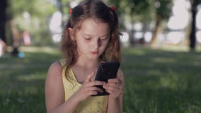 Dziewczyna w parku komunikuje z przyjaciółmi w ogólnospołecznych sieciach używać smartphone Uśmiechnięty nastolatek w gadce używa zdjęcie wideo Dziewczyna w parku komunikuje z przyjaciółmi w ogólnospołecznych sieciach używać smartphone Uśmiechnięty nastolatek w gadce używa zdjęcie wideo