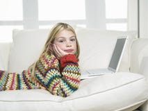 Dziewczyna Z ręką Na podbródku Używać laptop Na kanapie obraz stock Dziewczyna Z ręką Na podbródku Używać laptop Na kanapie obraz stock