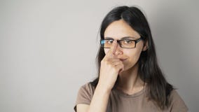 Dziewczyna z szkłami odizolowywającymi na popielatym ściennym tle zbiory wideo Dziewczyna z szkłami odizolowywającymi na popielatym ściennym tle zbiory wideo