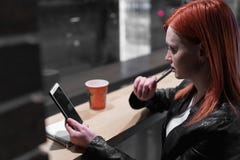 Dziewczyny mienia smartphone w r?ce, siedzi w kawiarni, dzia?anie, pi?ro, u?ywa gad?et Sie?, wifi, socjalny, komunikacja Freelanc zdjęcia stock Dziewczyny mienia smartphone w r?ce, siedzi w kawiarni, dzia?anie, pi?ro, u?ywa gad?et Sie?, wifi, socjalny, komunikacja Freelanc zdjęcia stock