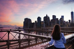 Dziewczyny spojrzenie przy Manhattan budynkami od Brooklin mosta przy świtem obrazy stock Dziewczyny spojrzenie przy Manhattan budynkami od Brooklin mosta przy świtem obrazy stock
