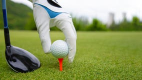 Dé poner la pelota de golf en camiseta en campo de golf imágenes de archivo libres de regalías Dé poner la pelota de golf en camiseta en campo de golf imágenes de archivo libres de regalías