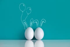 Easter eggs painted with ears and balloons on the blue background
