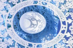 Easter. A lovely Easter card with an openwork oval frame through which beautiful shadows fall on a white egg. Blue background, top royalty free stock photography Easter. A lovely Easter card with an openwork oval frame through which beautiful shadows fall on a white egg. Blue background, top royalty free stock photography