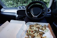 Eating food on the move in car due to busy stressful work life being unhealthy stock images Eating food on the move in car due to busy stressful work life being unhealthy stock images