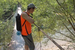 Eco tourism and healthy lifestyle concept. Young hiker boy with backpack. Traveler travel on the suspension bridge go trekking tog stock photos Eco tourism and healthy lifestyle concept. Young hiker boy with backpack. Traveler travel on the suspension bridge go trekking tog stock photos