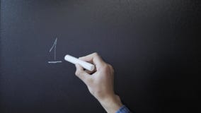 Education concept. Hand holding chalk and writing 12345 numbers on chalkboard. Equation on Blackboard. School blackboard concept