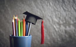 Educação e de volta ao conceito da escola com o tampão da graduação na cor dos lápis em uma caixa de lápis no fundo escuro imagens de stock Educação e de volta ao conceito da escola com o tampão da graduação na cor dos lápis em uma caixa de lápis no fundo escuro imagens de stock