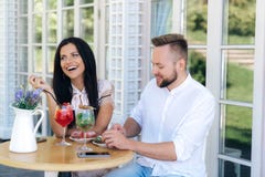 Een aantrekkelijk vrolijk meisje kwam een aardige modieuze kerel zien een paar rust in een koffie, etend matrijzen, die spreken e royalty-vrije stock afbeelding Een aantrekkelijk vrolijk meisje kwam een aardige modieuze kerel zien een paar rust in een koffie, etend matrijzen, die spreken e royalty-vrije stock afbeelding