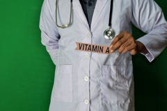Een arts die, houdt de Vitamine Adocument tekst op Groene achtergrond bevinden zich Medisch en gezondheidszorgconcept stock fotografie Een arts die, houdt de Vitamine Adocument tekst op Groene achtergrond bevinden zich Medisch en gezondheidszorgconcept stock fotografie