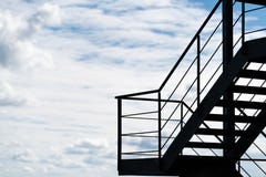 Een brandtrap of een externe die trap op een gebouw tegen een bewolkte hemel wordt gesilhouetteerd royalty-vrije stock afbeelding Een brandtrap of een externe die trap op een gebouw tegen een bewolkte hemel wordt gesilhouetteerd royalty-vrije stock afbeelding