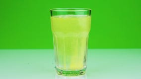 Een bruisende tablet tegen pijn valt in een glas en lost Close-up slow-motion schot van aspirin op green op stock videobeelden Een bruisende tablet tegen pijn valt in een glas en lost Close-up slow-motion schot van aspirin op green op stock videobeelden