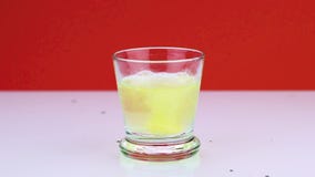 Een bruisende tablet tegen pijn valt in een glas en lost slow-motion schot van aspirin op een rode achtergrond op stock videobeelden Een bruisende tablet tegen pijn valt in een glas en lost slow-motion schot van aspirin op een rode achtergrond op stock videobeelden