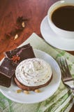 Een cake met eiwitroom, stukken van chocolade, anijsplant, kardemom op een groen servet en een kop van hete koffie stock afbeelding Een cake met eiwitroom, stukken van chocolade, anijsplant, kardemom op een groen servet en een kop van hete koffie stock afbeelding