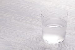 Een close-upbeeld van een nat stomend half volledig glas water Op een witte houten lijst royalty-vrije stock fotografie Een close-upbeeld van een nat stomend half volledig glas water Op een witte houten lijst royalty-vrije stock fotografie