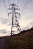 Een donkere grote transmissietoren, elektriciteitspyloon, bevindt zich tegen een gele zonsondergang stock afbeelding Een donkere grote transmissietoren, elektriciteitspyloon, bevindt zich tegen een gele zonsondergang stock afbeelding