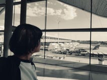 Een eenzame vrouw in de luchthaven bekijkt het landingsterrein stock foto's Een eenzame vrouw in de luchthaven bekijkt het landingsterrein stock foto's