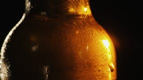 Een fles koud bier op een zwarte achtergrond Een straal van licht verlicht het prachtig royalty-vrije stock afbeelding Een fles koud bier op een zwarte achtergrond Een straal van licht verlicht het prachtig royalty-vrije stock afbeelding
