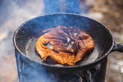 Een gebrande pannekoek in een pan Het koken in openlucht op de brand stock fotografie Een gebrande pannekoek in een pan Het koken in openlucht op de brand stock fotografie