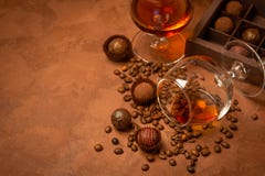 Een glas van sterke alcoholisch drinkt brandewijn of brandewijn en suikergoed van donkere chocolade op een bruine geweven achterg stock foto Een glas van sterke alcoholisch drinkt brandewijn of brandewijn en suikergoed van donkere chocolade op een bruine geweven achterg stock foto