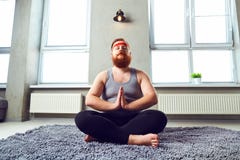 Een grappige vette gebaarde mens in sportenkleren doet yoga in de ruimte Stock Afbeeldingen Een grappige vette gebaarde mens in sportenkleren doet yoga in de ruimte Stock Afbeeldingen