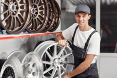 Een jonge en aantrekkelijke autowerktuigkundige kiest een bandrand royalty-vrije stock foto's Een jonge en aantrekkelijke autowerktuigkundige kiest een bandrand royalty-vrije stock foto's