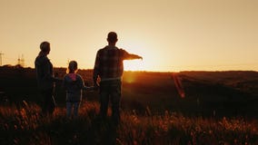 Een jonge familie - het mamma, de papa en de dochter bekijken samen de zonsondergang Gelukkig samen, silhouetten bij zonsondergan stock video Een jonge familie - het mamma, de papa en de dochter bekijken samen de zonsondergang Gelukkig samen, silhouetten bij zonsondergan stock video