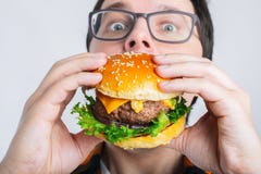 Een jonge kerel houdt een verse Hamburger Een zeer hongerige student eet snel voedsel Heet nuttig voedsel Het concept gulzigheid royalty-vrije stock afbeelding Een jonge kerel houdt een verse Hamburger Een zeer hongerige student eet snel voedsel Heet nuttig voedsel Het concept gulzigheid royalty-vrije stock afbeelding