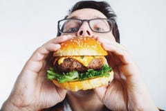 Een jonge kerel houdt een verse Hamburger Een zeer hongerige student eet snel voedsel Heet nuttig voedsel Het concept gulzigheid stock foto Een jonge kerel houdt een verse Hamburger Een zeer hongerige student eet snel voedsel Heet nuttig voedsel Het concept gulzigheid stock foto