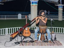 Een jonge kerel speelt een fluit in de avond op de waterkant in de stad van Nahariya, in Israël stock fotografie Een jonge kerel speelt een fluit in de avond op de waterkant in de stad van Nahariya, in Israël stock fotografie
