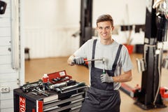 Een jonge knappe werktuigkundige is bij zijn werk terwijl het voorbereidingen treffen voor het herstellen van een auto royalty-vrije stock foto Een jonge knappe werktuigkundige is bij zijn werk terwijl het voorbereidingen treffen voor het herstellen van een auto royalty-vrije stock foto