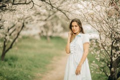 Een jonge vrouw bevindt zich onder de tot bloei komende tuin royalty-vrije stock afbeelding Een jonge vrouw bevindt zich onder de tot bloei komende tuin royalty-vrije stock afbeelding