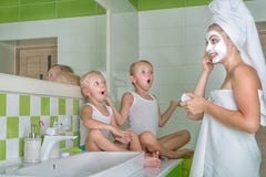 Een jonge vrouw maakt een gezichtsmasker Kinderen die op de moeder, verraste gezichten letten Schoonheidsbehandelingen voor de hu royalty-vrije stock fotografie Een jonge vrouw maakt een gezichtsmasker Kinderen die op de moeder, verraste gezichten letten Schoonheidsbehandelingen voor de hu royalty-vrije stock fotografie
