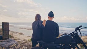Een jonge vrouw met haar vriend, de ruiter en zijn motorfiets bewonderen samen de prachtige mening rond, berg en stock video Een jonge vrouw met haar vriend, de ruiter en zijn motorfiets bewonderen samen de prachtige mening rond, berg en stock video