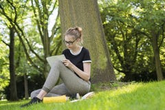 Een jonge vrouwenzitting onder een boom en schrijft in een omslag stock foto's Een jonge vrouwenzitting onder een boom en schrijft in een omslag stock foto's