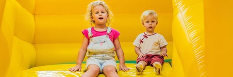 Een jongen en een meisje berijden van een opblaasbare diabanner, LANG FORMAAT royalty-vrije stock afbeelding Een jongen en een meisje berijden van een opblaasbare diabanner, LANG FORMAAT royalty-vrije stock afbeelding