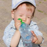 Een kind drinkt water van een fles Het kind, de jongen, dooft stock foto Een kind drinkt water van een fles Het kind, de jongen, dooft stock foto