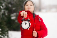 Een kindjongen houdt een klokwekker in zijn handen De winter D stock fotografie Een kindjongen houdt een klokwekker in zijn handen De winter D stock fotografie