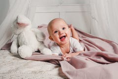 Een kleine baby legt op een bed met een stuk speelgoed konijn en glimlacht royalty-vrije stock foto's Een kleine baby legt op een bed met een stuk speelgoed konijn en glimlacht royalty-vrije stock foto's