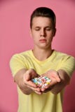 Een knappe mens in T-shirt op een roze achtergrondholdingspillen in zijn hand stock fotografie Een knappe mens in T-shirt op een roze achtergrondholdingspillen in zijn hand stock fotografie