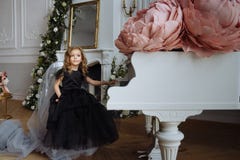 Een meisje in een mooie kleding op een stoel dichtbij de piano stock foto Een meisje in een mooie kleding op een stoel dichtbij de piano stock foto