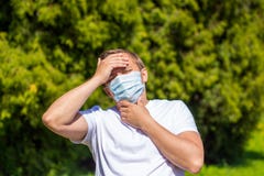 Een mens in een masker van allergie, in een witte T-shirt, bevindt zich in het park royalty-vrije stock fotografie Een mens in een masker van allergie, in een witte T-shirt, bevindt zich in het park royalty-vrije stock fotografie
