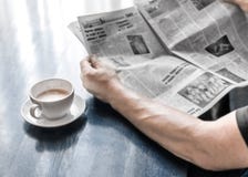 Een mensenlezing krant en het drinken koffiezitting in koffie of thuis in keuken in ochtendtijd Een koffiekop op dark royalty-vrije stock afbeelding Een mensenlezing krant en het drinken koffiezitting in koffie of thuis in keuken in ochtendtijd Een koffiekop op dark royalty-vrije stock afbeelding