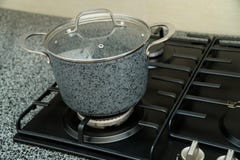 Een middelgrote pan op een zwart gasfornuis stock afbeelding Een middelgrote pan op een zwart gasfornuis stock afbeelding