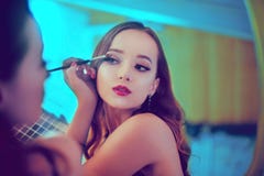 Een mooie jonge vrouw doet zich een makeover Meisje met cerly haar die avondmake-up doen gebruikend borstel en oogschaduw i royalty-vrije stock fotografie Een mooie jonge vrouw doet zich een makeover Meisje met cerly haar die avondmake-up doen gebruikend borstel en oogschaduw i royalty-vrije stock fotografie